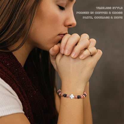 Woman praying wearing white mother-of-pearl cross magnetic copper bead bracelet for faith and hope

