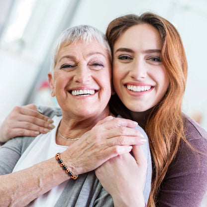 Smiling mother and daughter hugging while mother wears magnetic copper bead bracelet