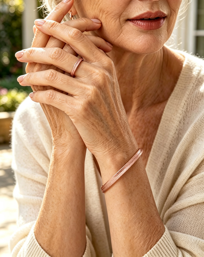 Woman wearing rose gold feather engraved copper cuff bracelet and matching leaf ring with cream cardigan
