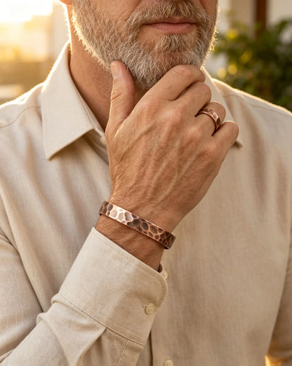 Mature man wearing hammered copper cuff bracelet and matching ring with beige linen shirt
