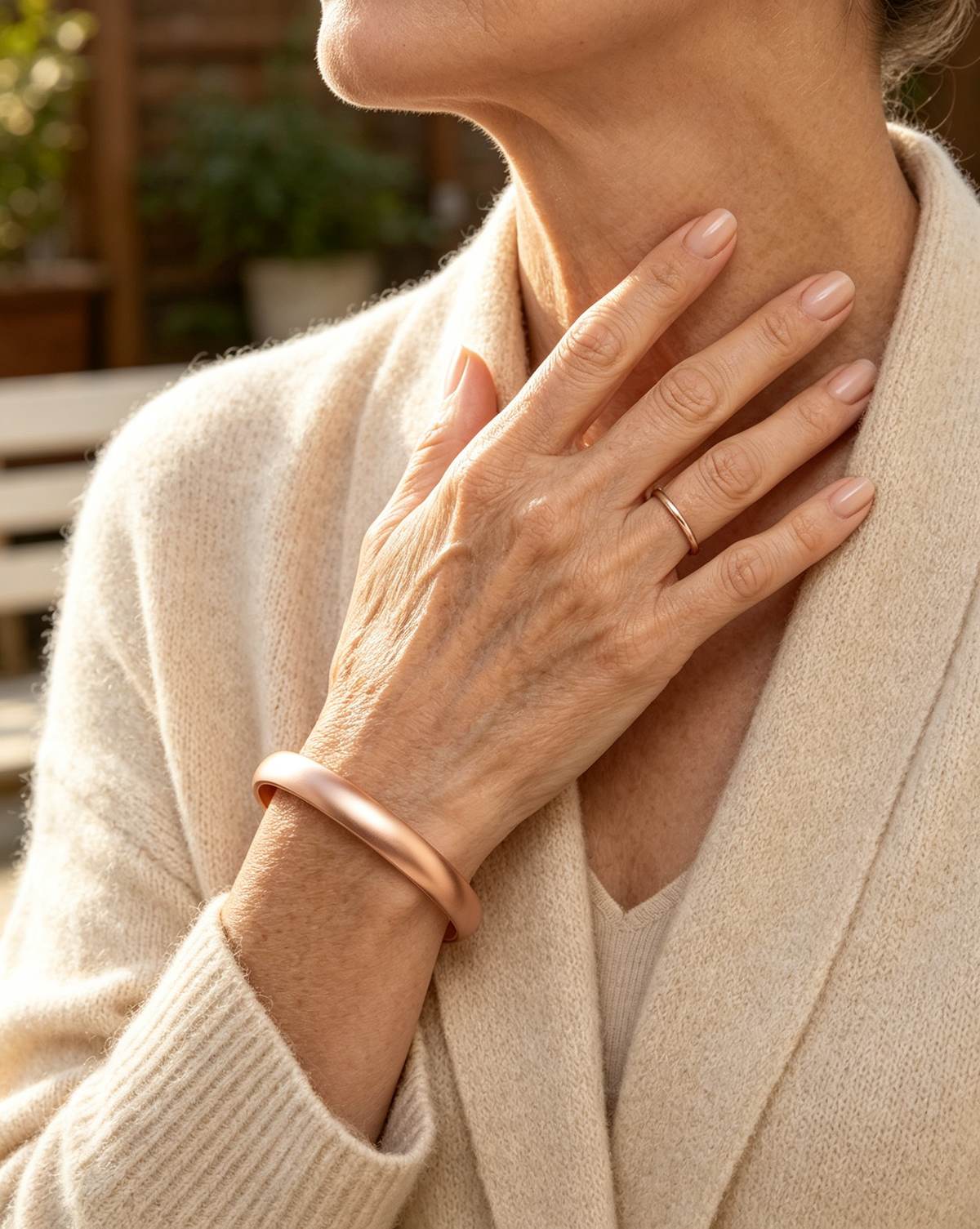 Woman wearing elegant rose gold copper cuff bracelet and matching ring with cream knit cardigan