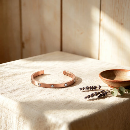 Solid copper Cuff bracelet with bezel-set sparkly cubic zirconia crystals on textured linen display