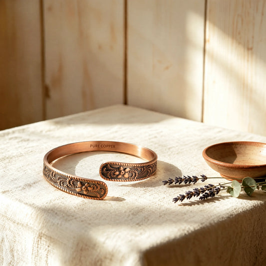 Petite Blossom pure copper cuff bangle featuring embossed floral motifs on textured linen display