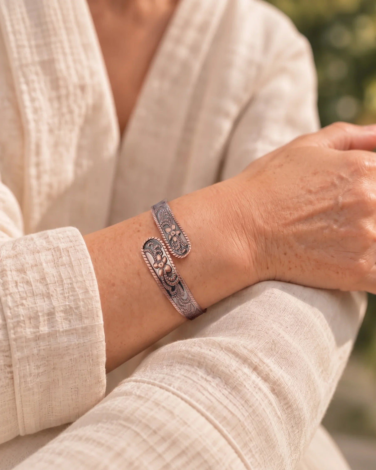 Woman wearing the adjustable Petite Blossom floral pure copper bracelet on wrist for daily styling
