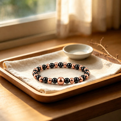 Magnetic copper beaded bracelet with 8mm center copper bead and black magnetic beads on wooden tray
