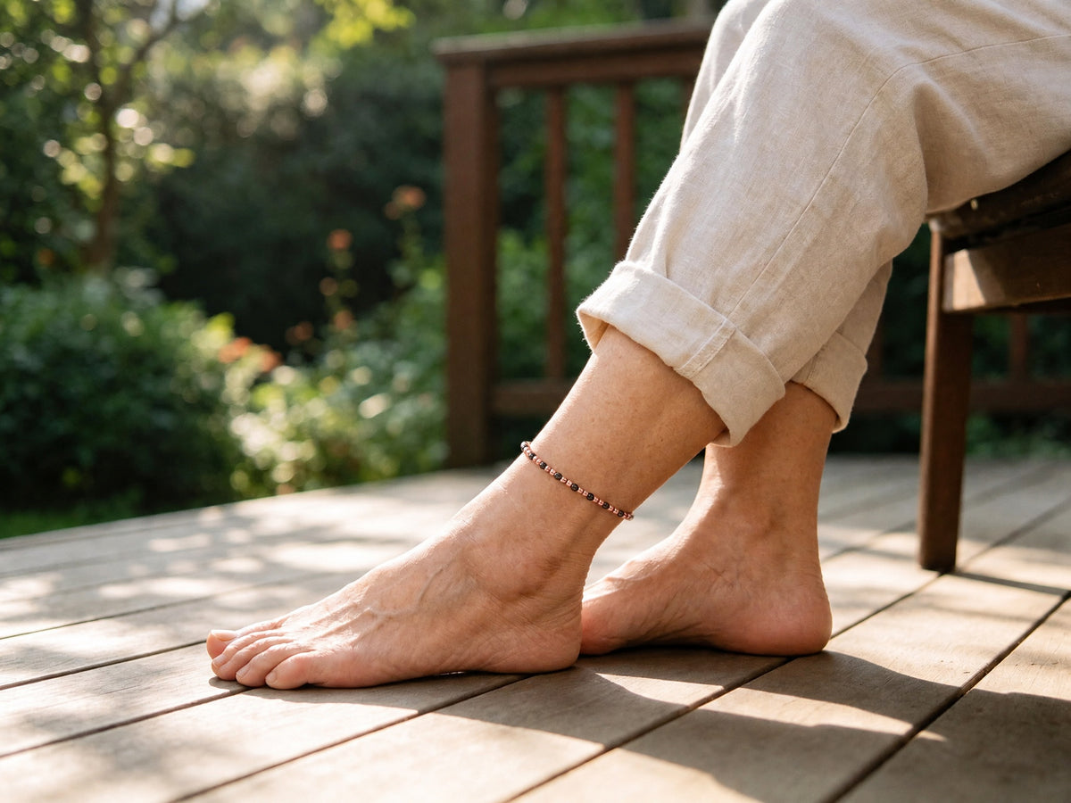 Person wearing 4mm magnetic copper beaded anklet on ankle relaxing outdoors on wooden deck